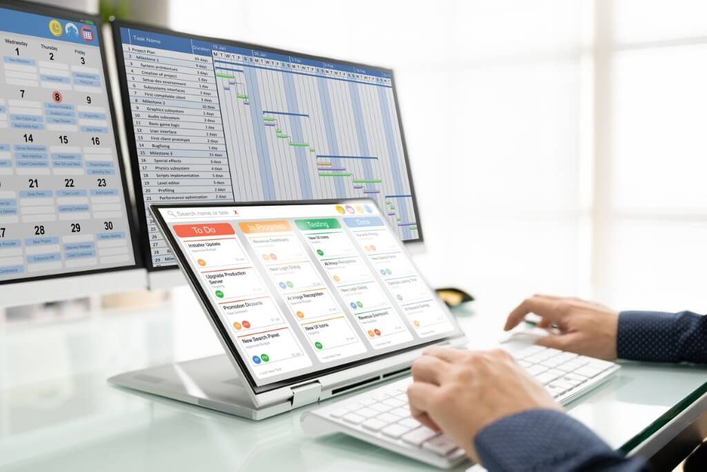 A person working on an applicant tracking system (ATS) displayed on a laptop and dual monitors, featuring task management tools, calendar scheduling, and project timelines. Relevant to recruitment software in UAE and hiring efficiency.