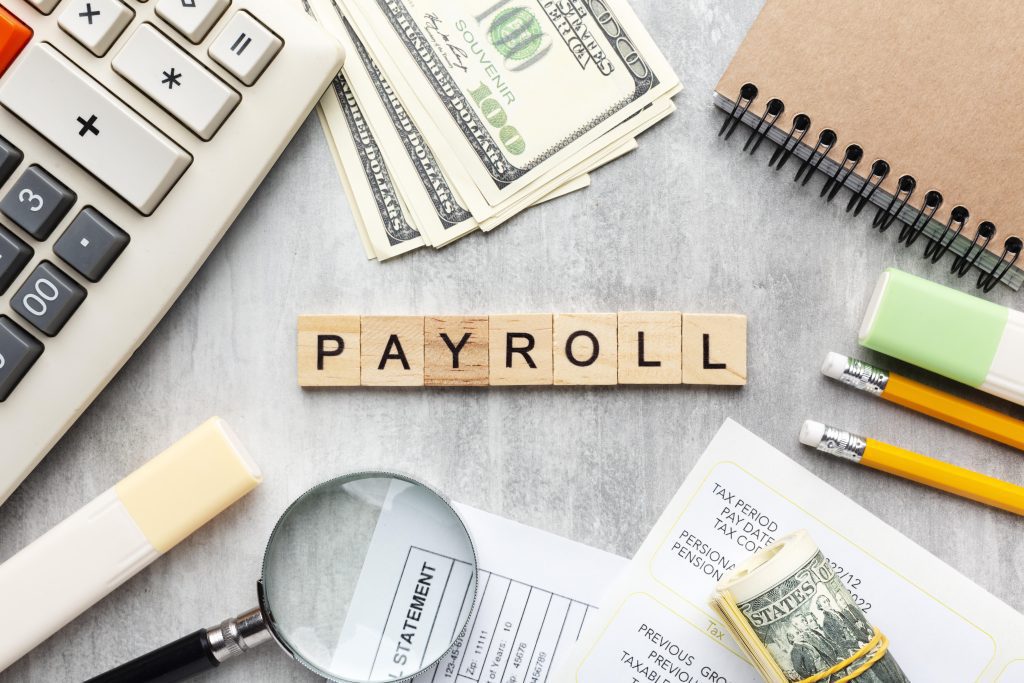 Best Payroll Services in UAE concept with calculator, cash, financial documents, and office supplies representing salary processing and payroll solutions.