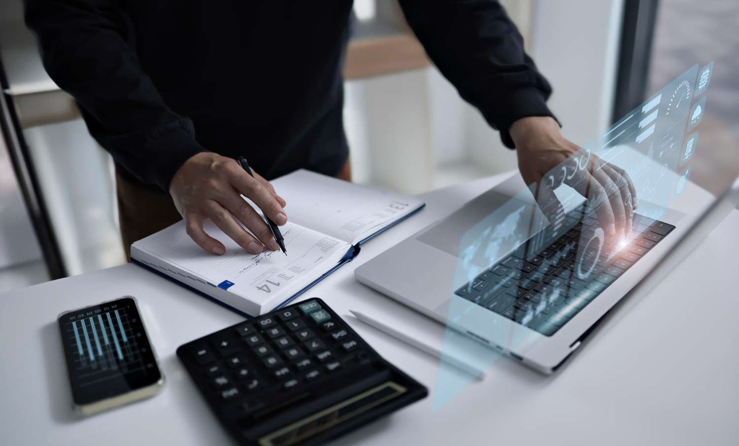 Business professional managing payroll tasks with notebook, calculator, and laptop, showcasing Payroll Software UAE automation technology.