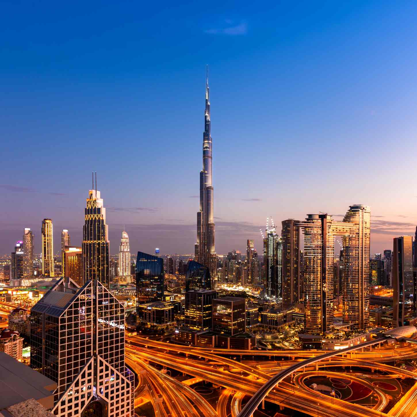 A stunning view of Dubai's skyline at dusk, featuring the Burj Khalifa and illuminated highways, representing the modern infrastructure ideal for implementing payroll software in Dubai, UAE, Middle East.