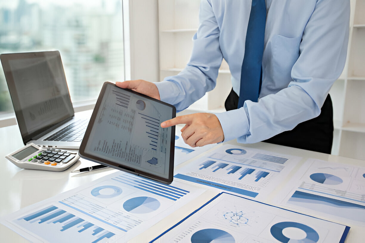 Business professional analyzing HR payroll software data on a tablet, surrounded by charts and documents