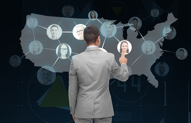 Businessman using recruitment software in Pakistan to select candidates on a digital map of the U.S. with connected profile photos representing applicant tracking.