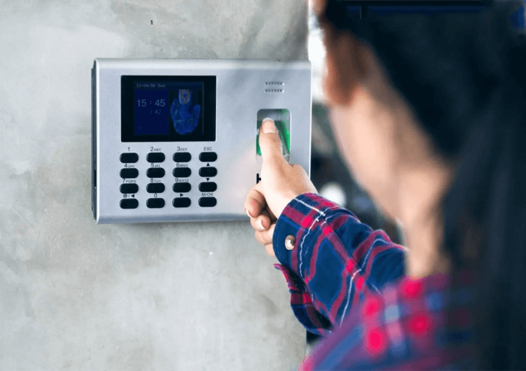 Employee using biometric fingerprint attendance solution in Pakistan office with facial recognition display showing modern workforce management technology